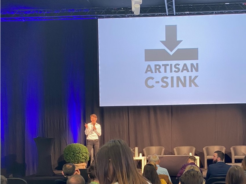 women-speaking-in-front-of-Artisan-c-sink-logo
